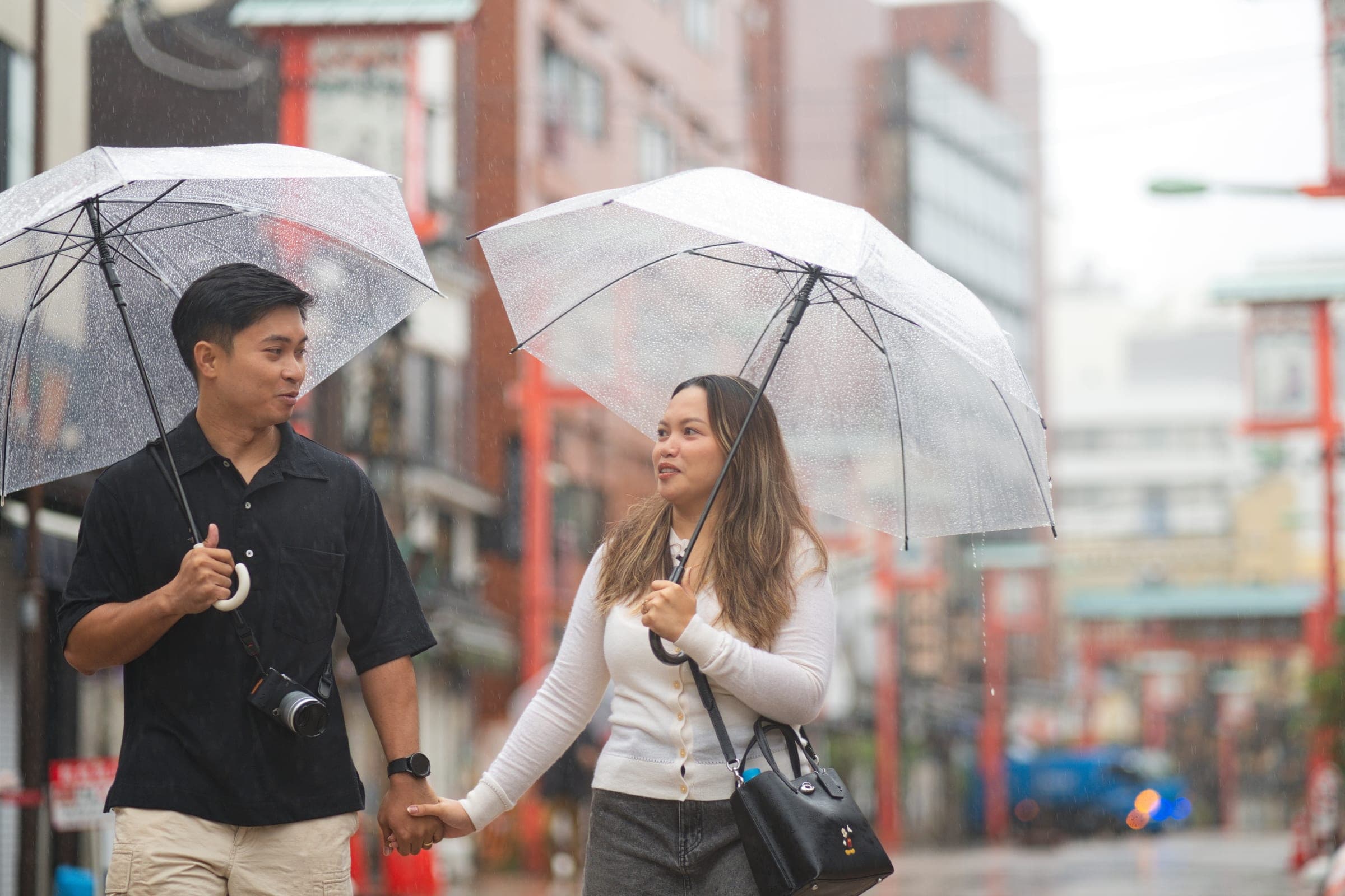 A couple sharing clear umbrellas on a rainy street in Asakusa