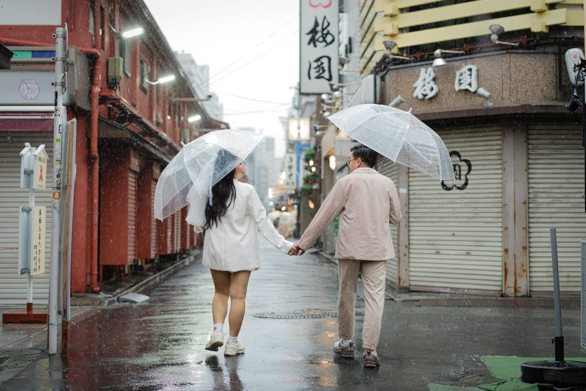 A couple walking away under a clear umbrella along a quiet Asakusa street
