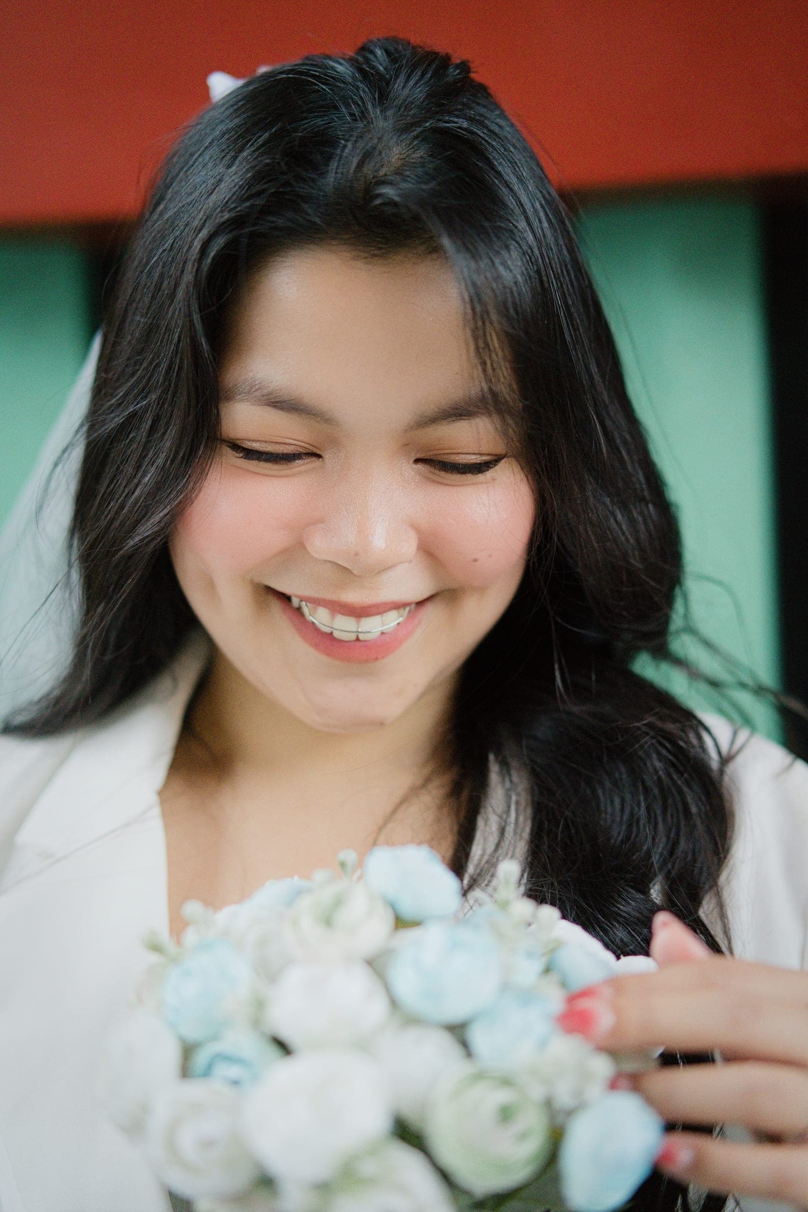 A woman holding white roses, smiling at the ring on her hand